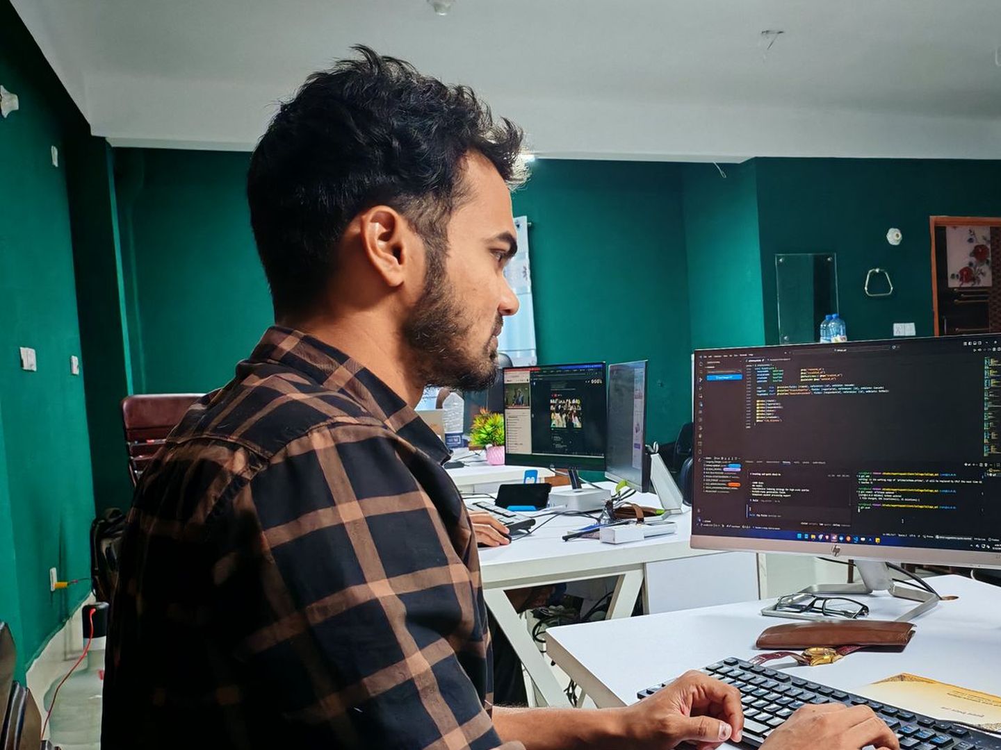 An engineer at his desk reading code on a monitor in an open office